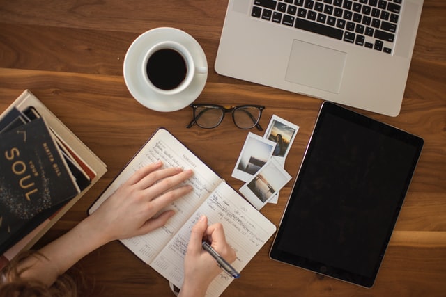 person holding a ballpoint pen writing in notebook