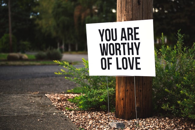 you are worthy of love sign near tree and road